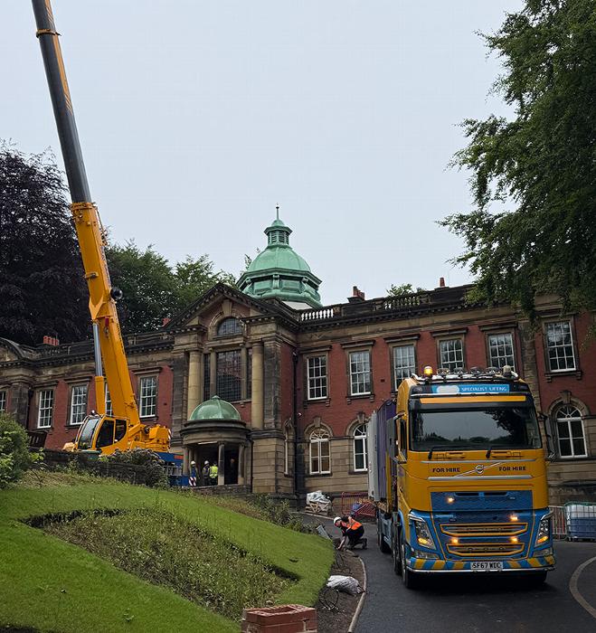 construction crane and truck in front of historic building with green dome and workers on site